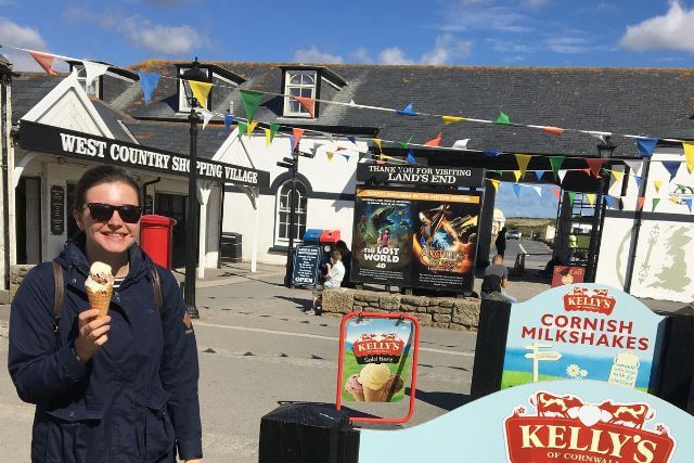 A smiling woman in sunglasses holds an ice cream at Land's End.