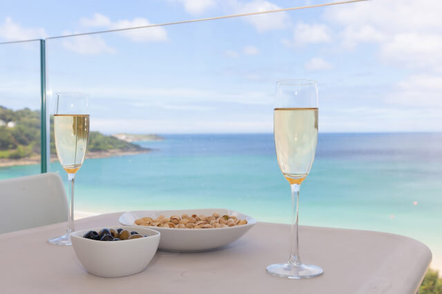 View of two prosecco glasses with snacks with Carbis Bay Beach in the background.