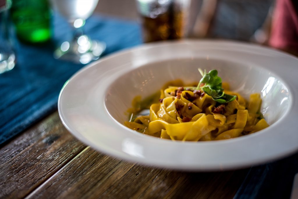 Linguine Bolognese on a white plate over a wooden in a St Ives Italian Restaurant