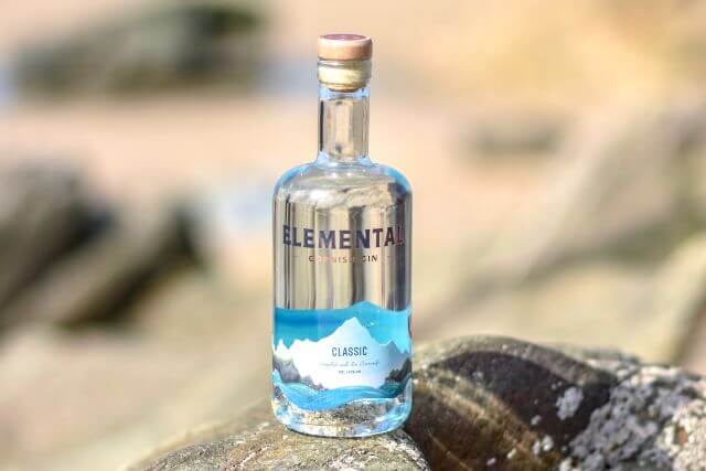 A bottle of Elemantal Cornish Gin on a rock in Cornwall.