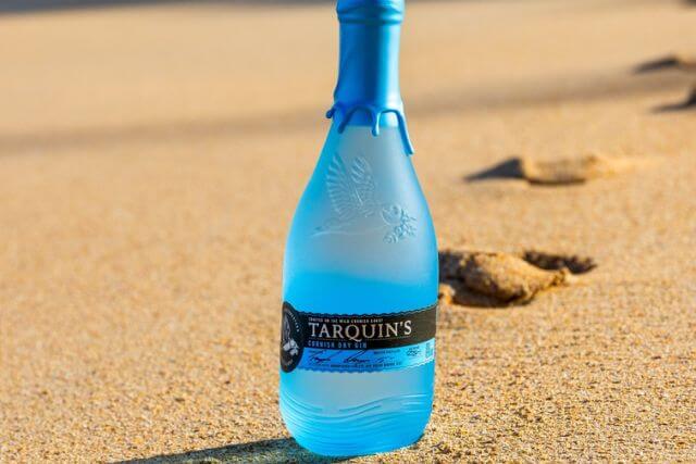 A bottle of Tarquin's Cornish Dry Gin on the beach.
