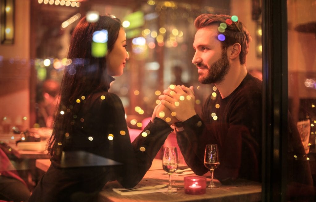 Woman and man romantically holding hands over Christmas dinner