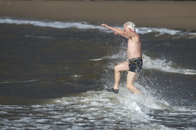 Older man runs into the sea.