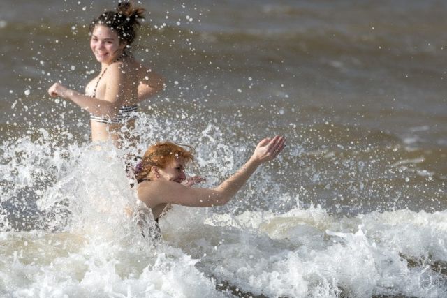 Two women run into the sea.