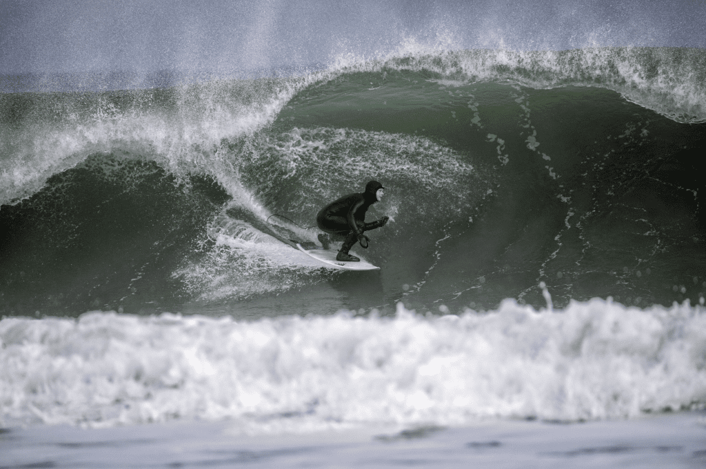 Cold water surfer wearing a hood surfing a wave