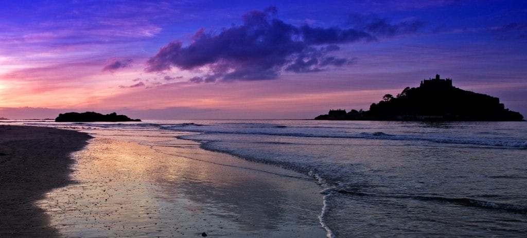 Sunset on mounts bay beach with St Micheals Mount silhouette in the distance.