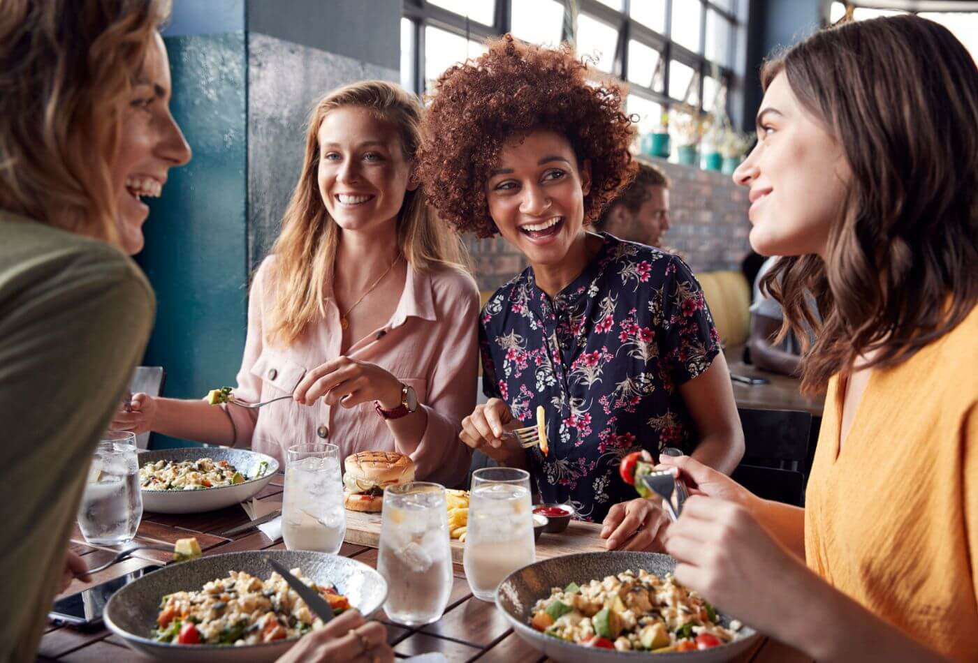 A group of women in a restaurant eating and talking.