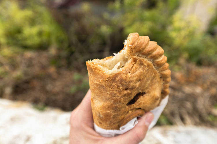 POV hand holding Cornish pasty in Charlestown, Cornwall