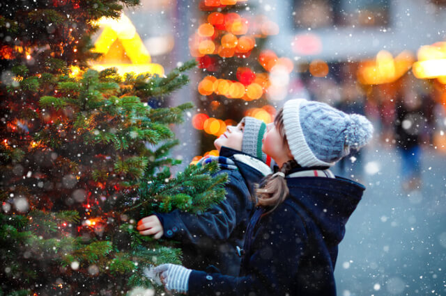 Children looking at a Christmas Tree in the snow.