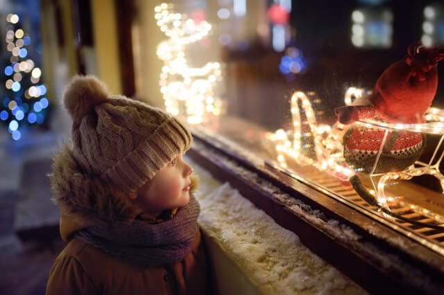 Little boy looking at a Christmas shop window.