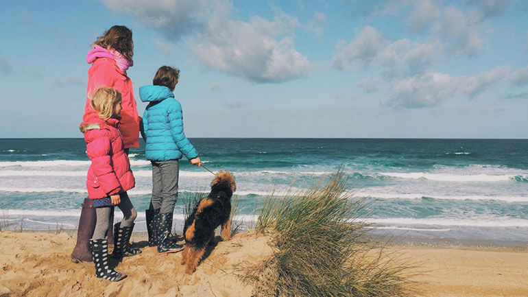 family with dog on beach in cornwall