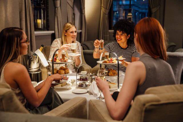 A group of four women friends enjoying afternoon tea in a restaurant.