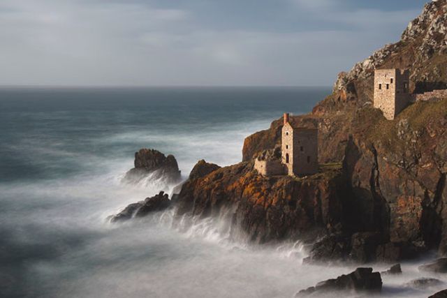 Dramatic winter coastal scene in Cornwall with waves crashing against rocks.