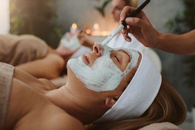 Woman in a spa having a face mask applied.