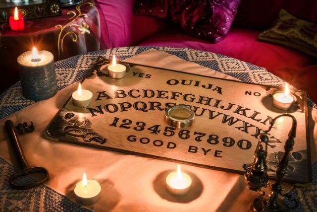 Spiritism table with a Ouija board and many lighted candles.