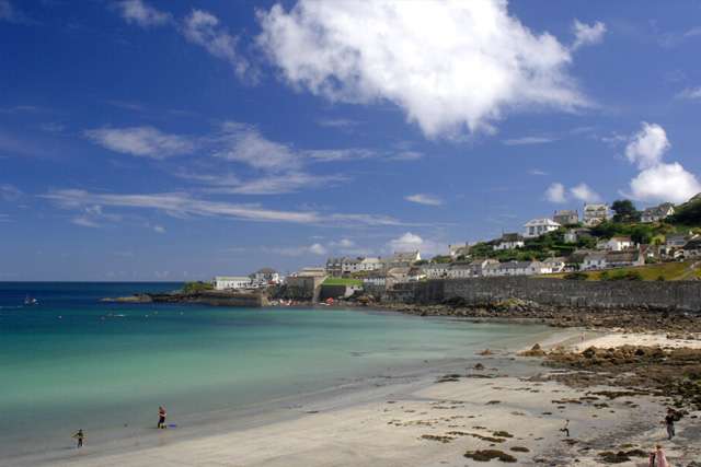 White sandy beach at coverack, with turquoise sea on the left and houses in the background